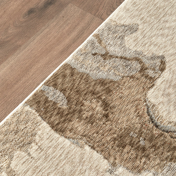 Close-up of soft-textured rug with abstract beige, brown, and gray shapes on a wood floor.