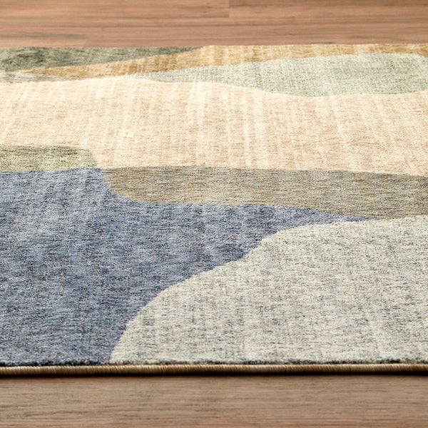 Tanami 336 rug with abstract multi-colored pattern in beige, blue, green, and gray tones on wooden floor.