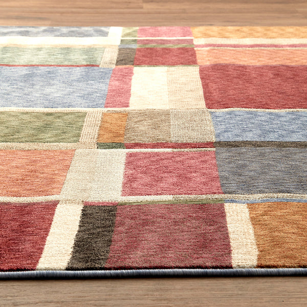 Multi-colored geometric patchwork rug in warm and cool tones with bold rectangular shapes.