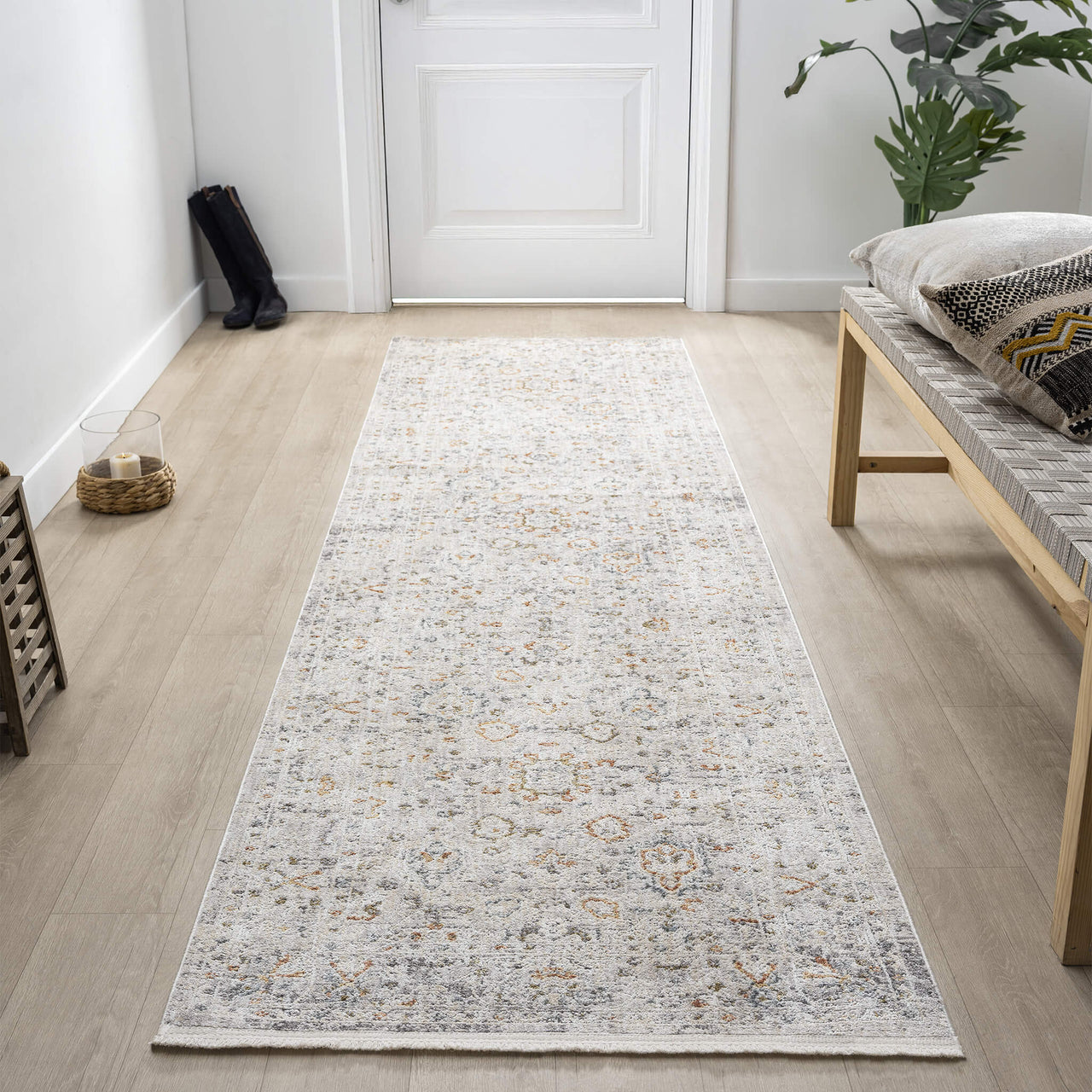 Patterned runner rug in an entrance with a wooden floor with a bench and plant in the background