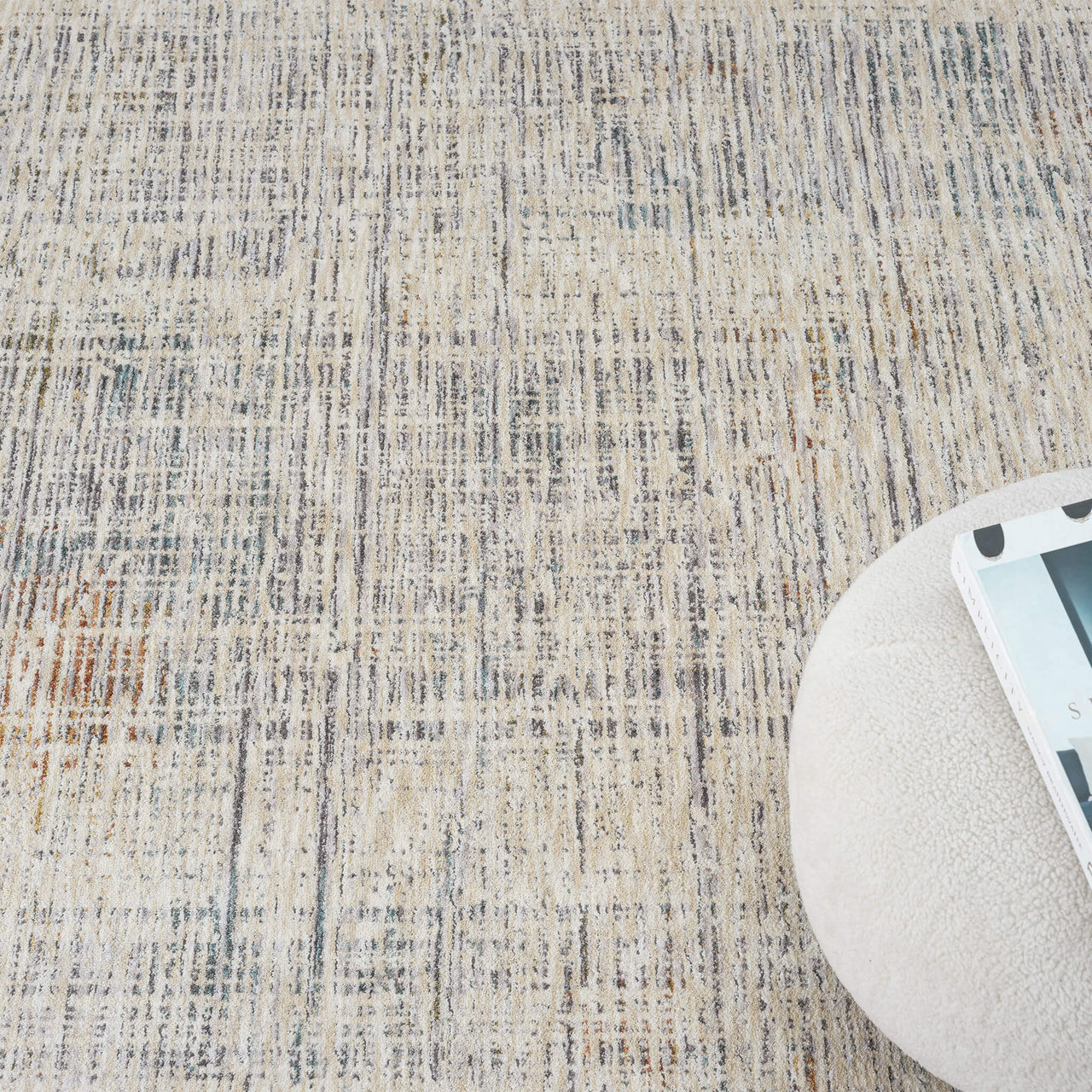 Textured beige rug with a round white ottoman partially visible