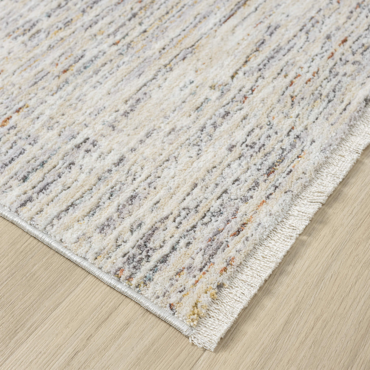 Textured area rug with a fringes and neutral pattern on a wooden floor