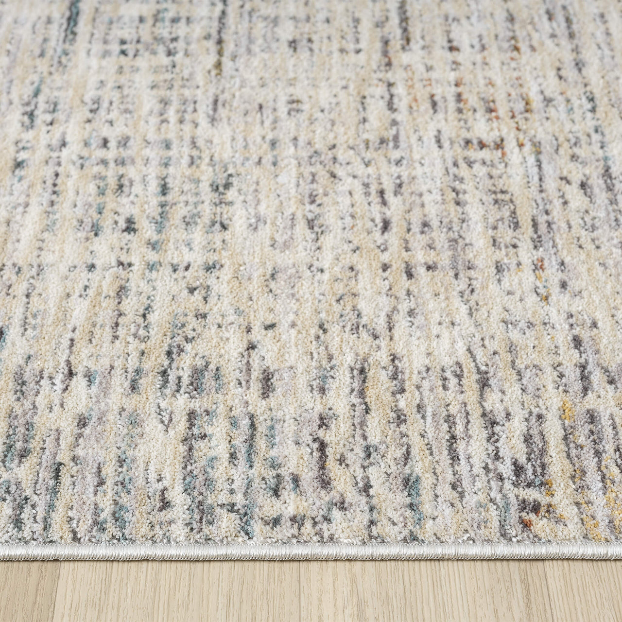 Close-up of a textured area rug with neutral colors on a wooden floor.