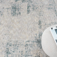 Textured area rug with a neutral color palette and a round ottoman corner.