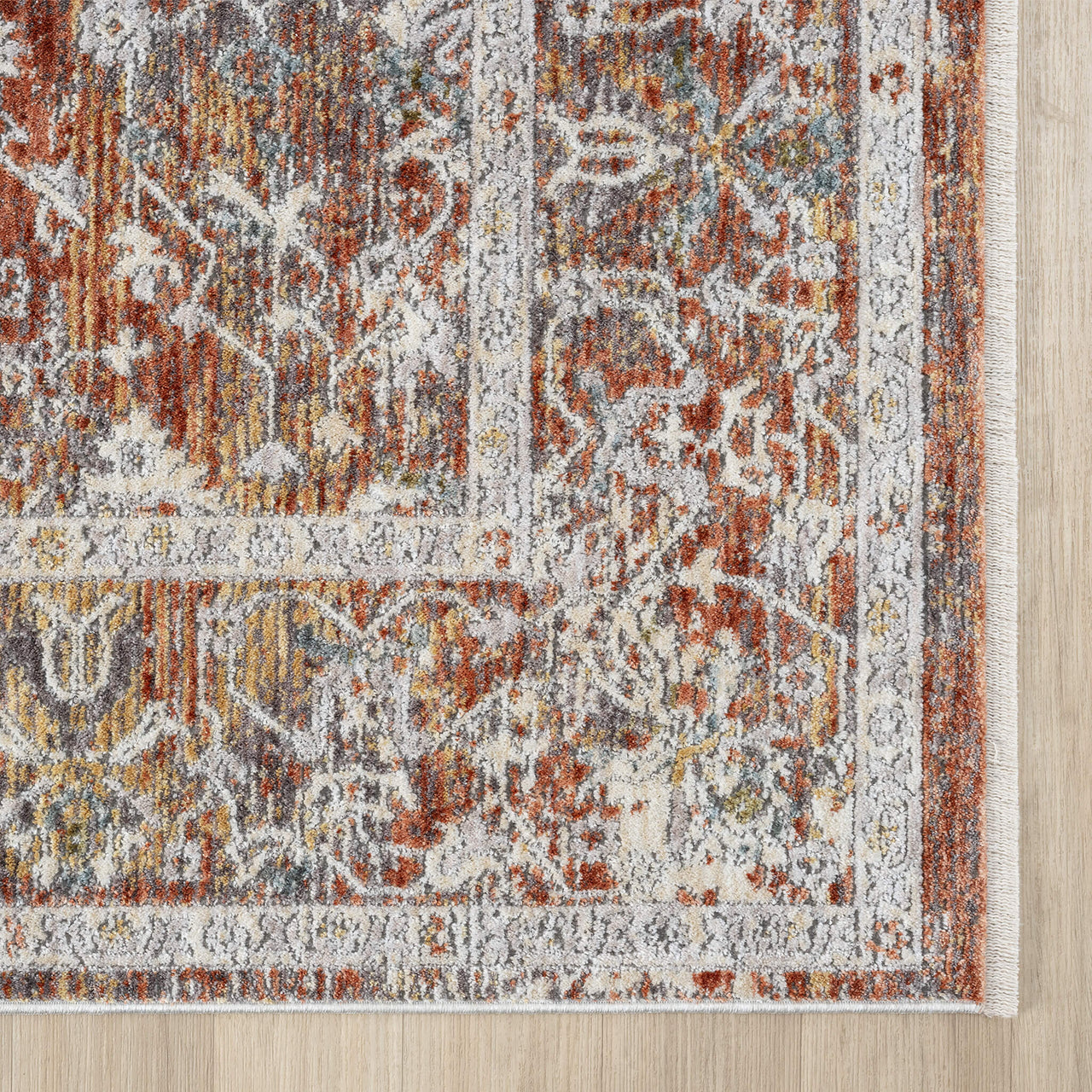 Close-up of a patterned rug with earthy tones on a wooden floor.