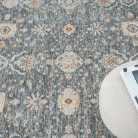 Blue transitional rug with intricate floral and geometric patterns in beige, cream, and rust tones on a textured background.