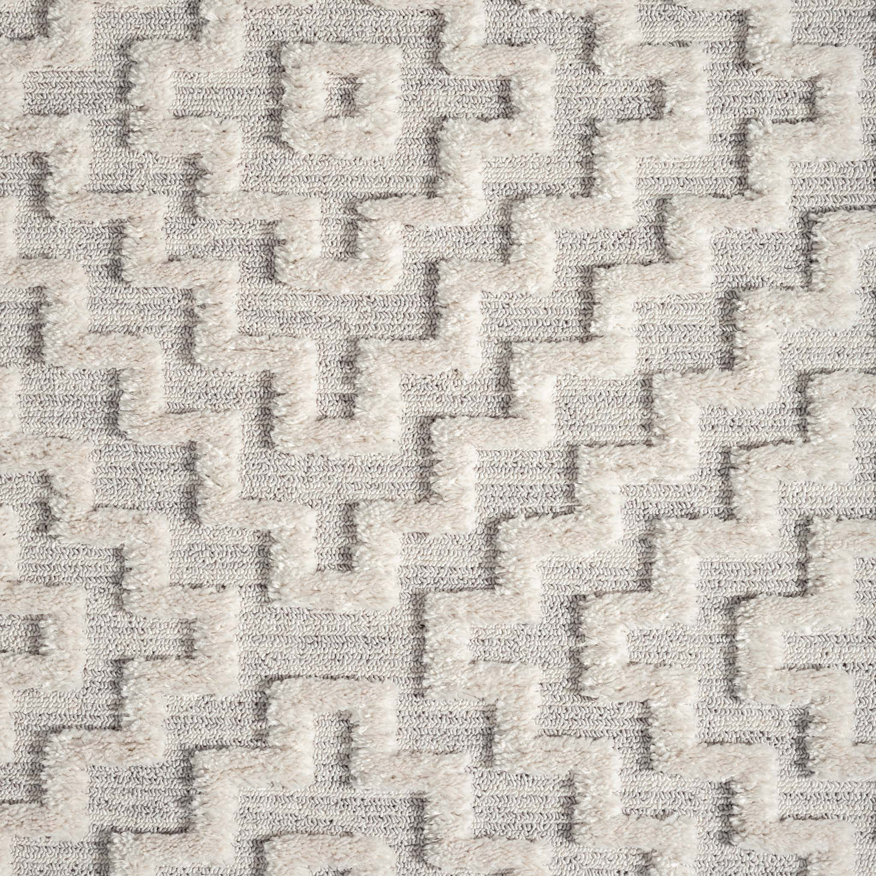Grey geometric patterned rug with raised textured pile and soft polyester fibers.