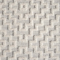 Grey geometric patterned rug with raised textured pile and soft polyester fibers.