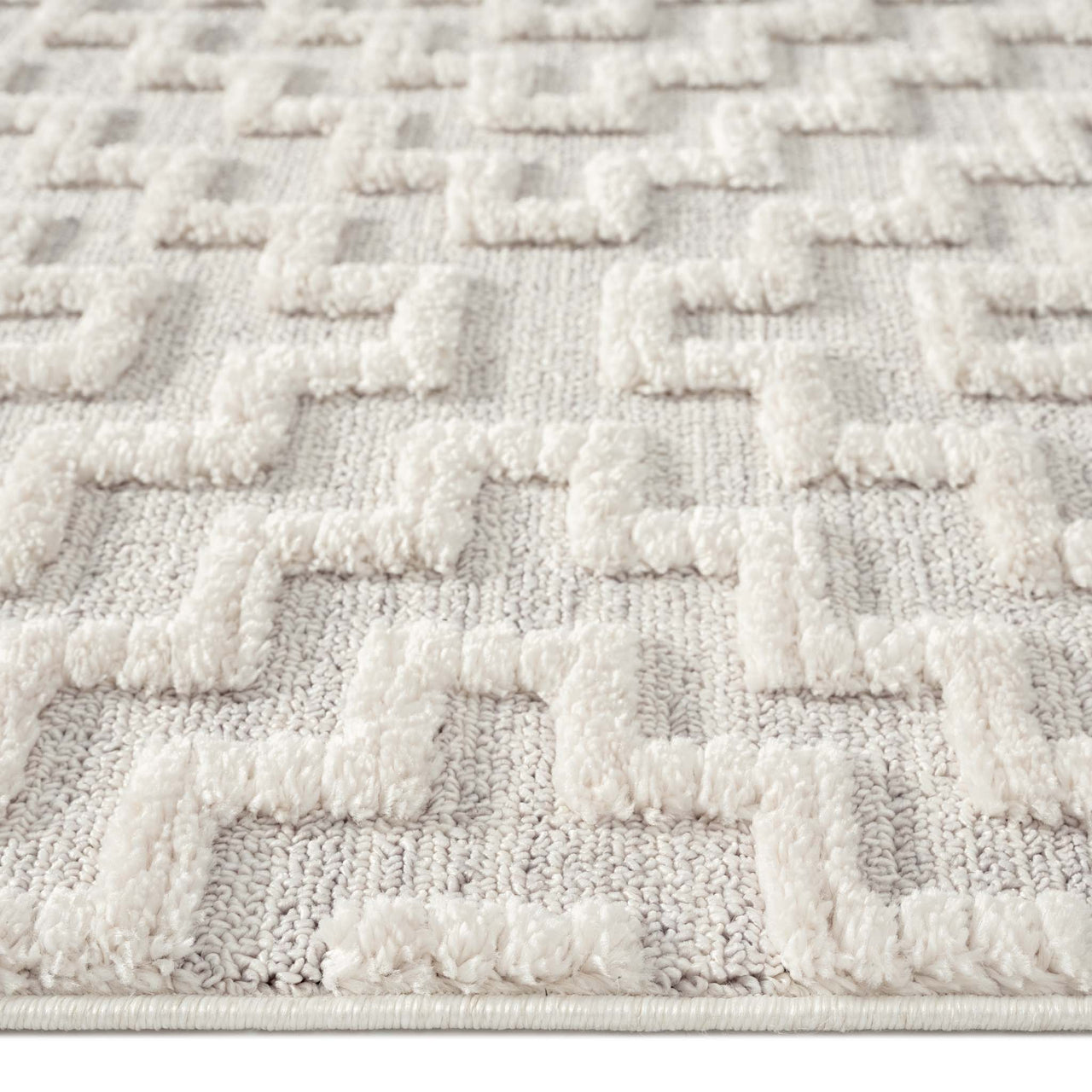 Grey rug with raised geometric textured pattern in soft polyester fibers.
