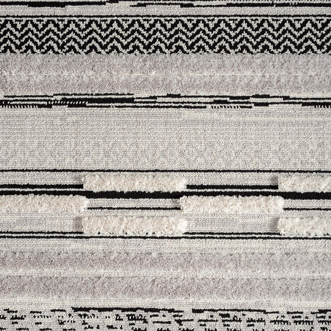 Grey geometric textured rug with abstract patterns and black accents, featuring a soft polyester pile.