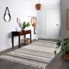 Grey geometric patterned rug with textured pile and fringed edges on hardwood floor.