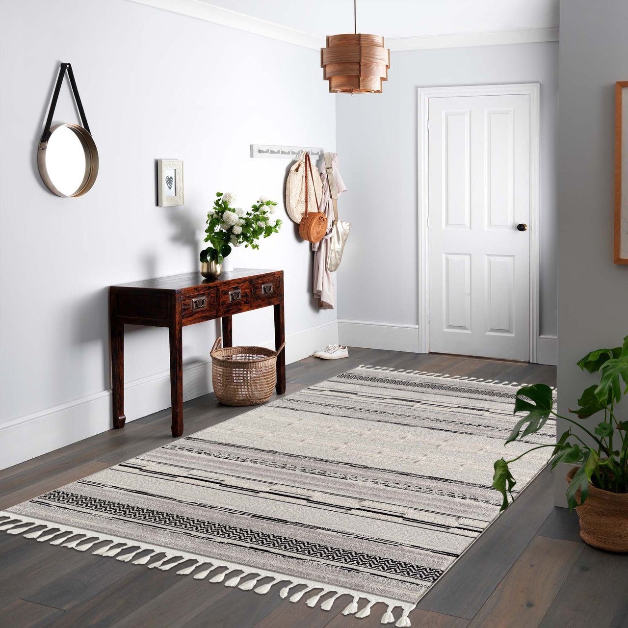 Grey geometric patterned rug with textured pile and fringed edges on hardwood floor.