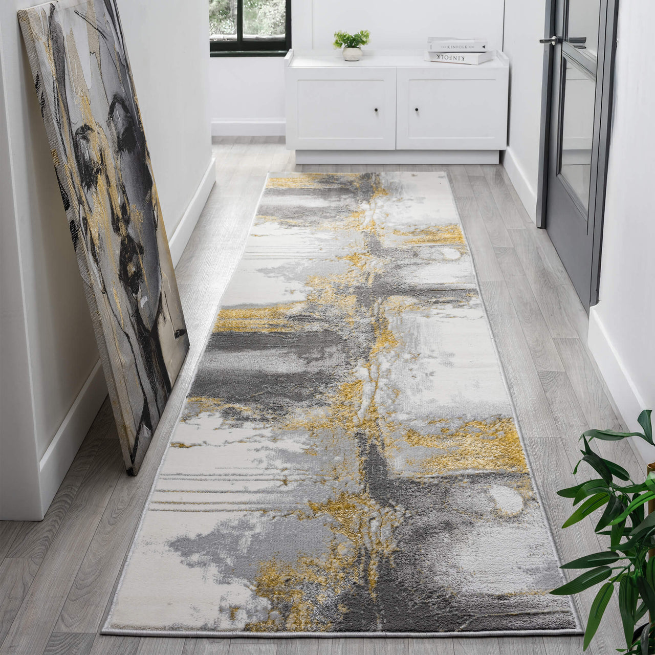 Grey, yellow, and white abstract patterned modern runner rug on light wood floor.