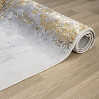 Rolled modern runner rug with abstract grey and gold pattern on soft polyester surface.