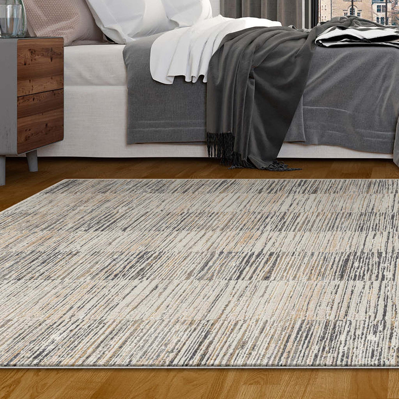 Modern neutral-toned rug with textured linear pattern on hardwood floor beside bed with gray and white bedding.