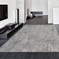 Grey blue modern patterned rug with subtle distressed texture on dark hardwood floor.