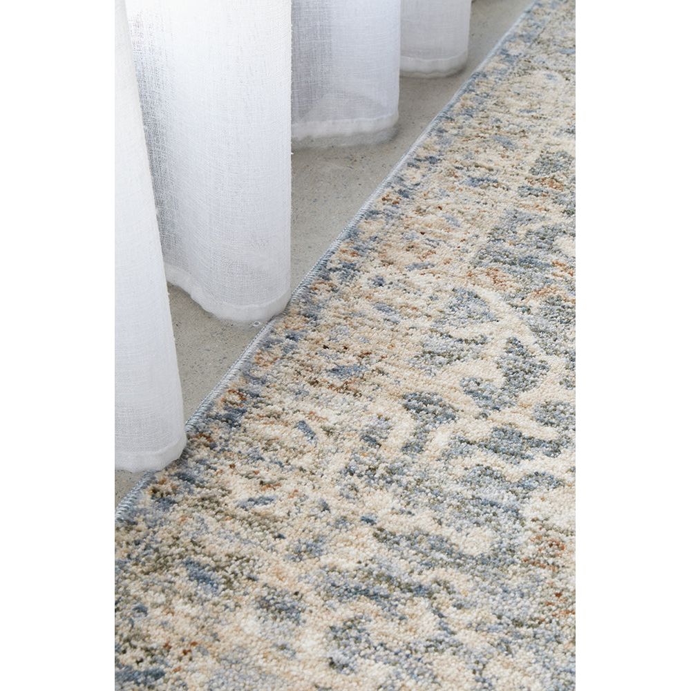 Patterned rug on a white floor with sheer curtains in the background