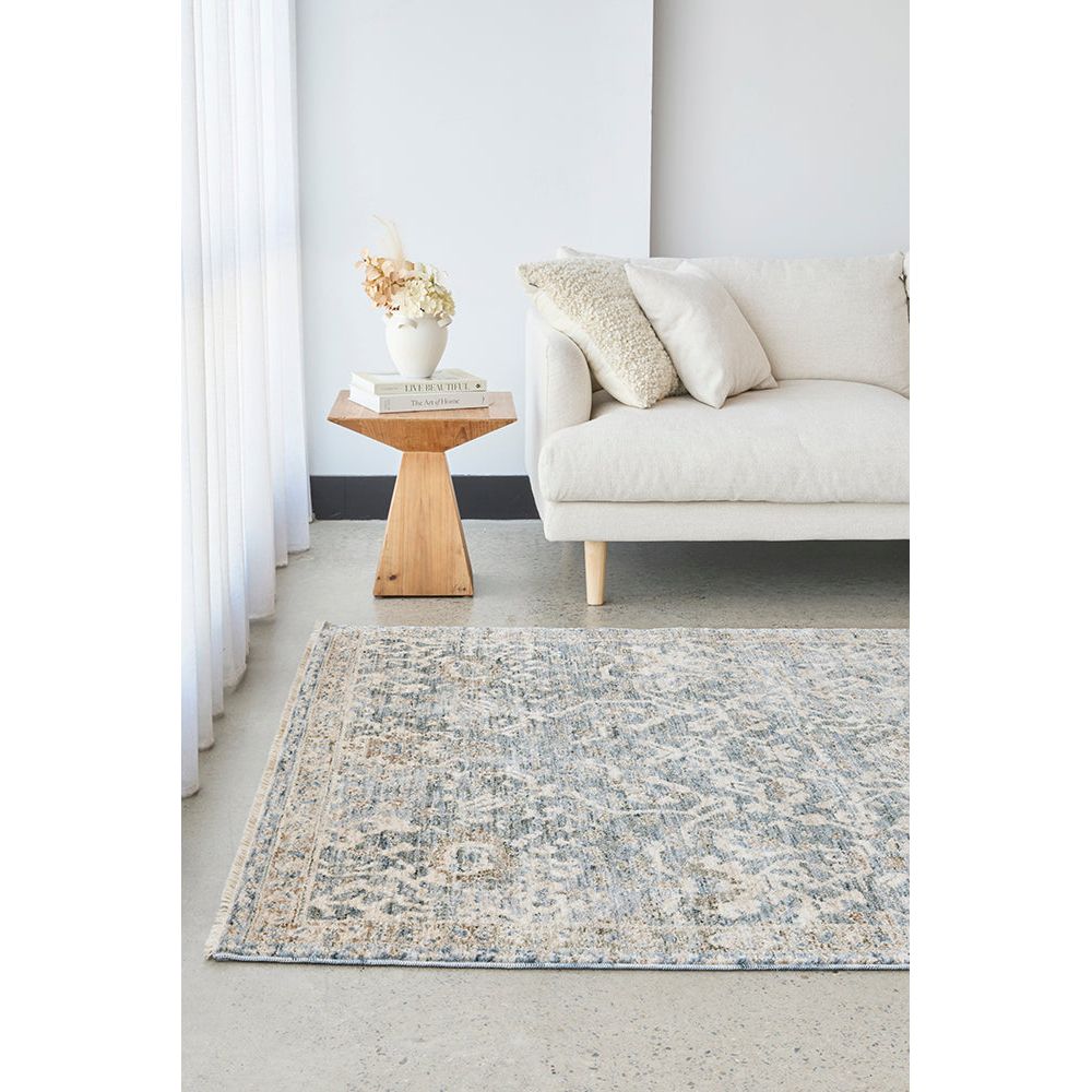 Living room with a patterned rug, beige sofa, and wooden side table.