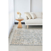 Living room with a patterned rug, beige sofa, and wooden side table.