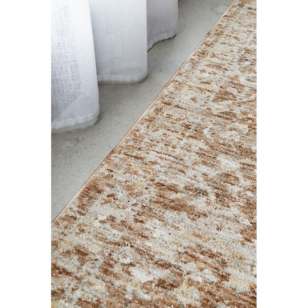 Close-up of a textured beige and brown rug on a concrete floor.