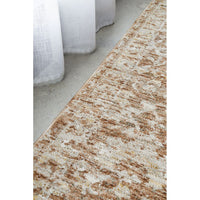 Close-up of a textured beige and brown rug on a concrete floor.