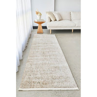 Long beige runner rug in a living room setting with a sofa and side table.