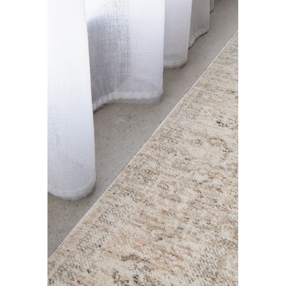 Close-up of a textured beige runner rug with white curtains in the background