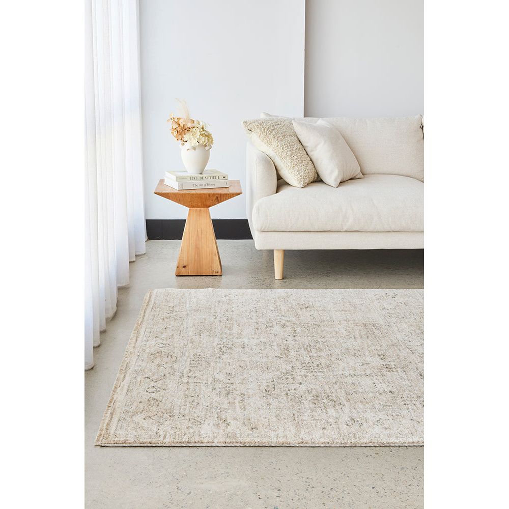 Living room with a beige rug, white sofa, and wooden side table.