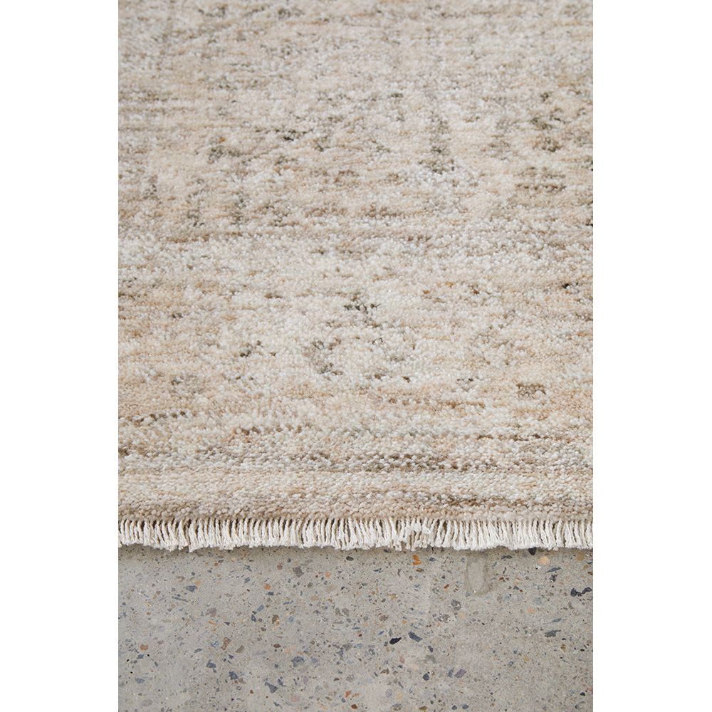 Close-up of a textured beige rug with a concrete floor underneath