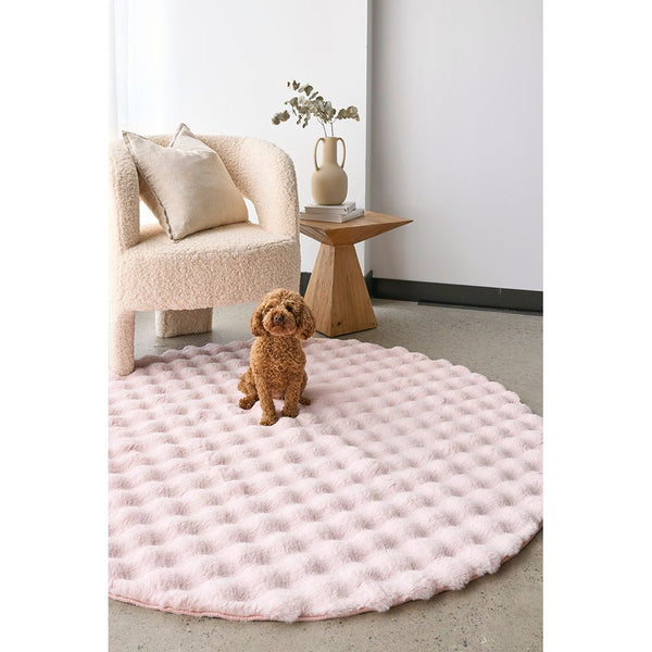 Round blush pink rug with raised bubble texture placed in modern living room setting.