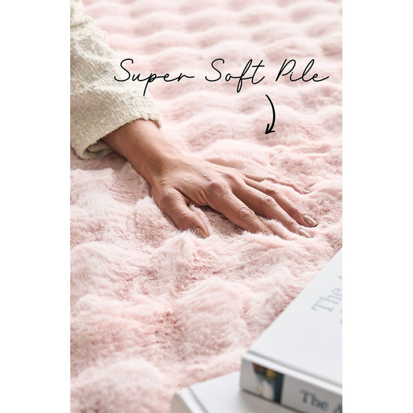 Blush pink plush rug with super soft textured pile and subtle wave pattern.