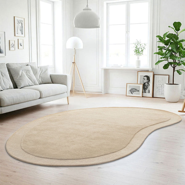 Beige bean-shaped modern curved wool rug with subtle border detail on light wood floor.