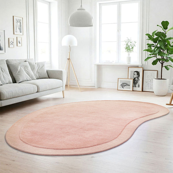 Pastel pink bean-shaped wool rug with soft curved edges in bright modern living room.