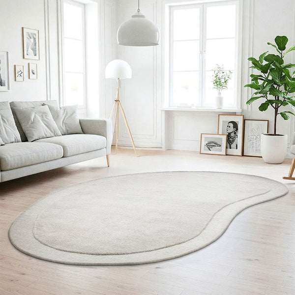 Light silver grey curved wool rug with soft pile in a bright modern living room setting.
