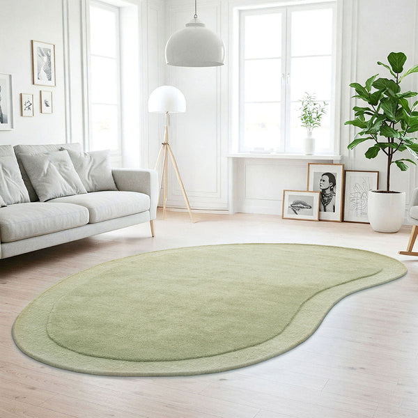 Soft green bean-shaped wool rug with curved edges on light wood floor in bright room.