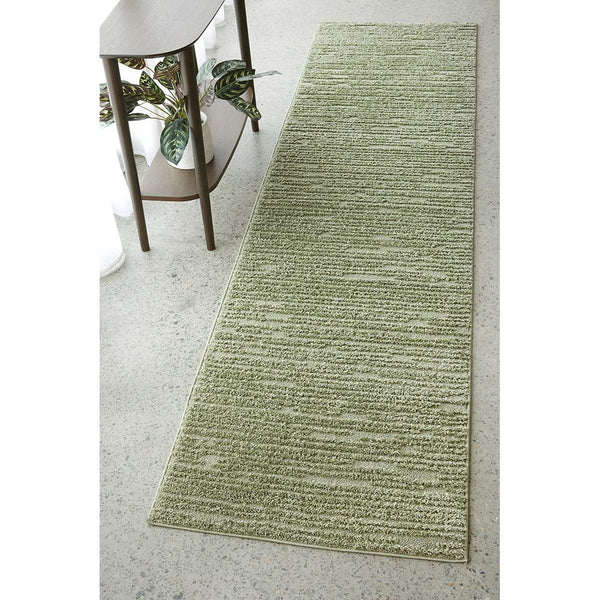 Emerald green runner rug with subtle diamond texture on polished concrete floor.