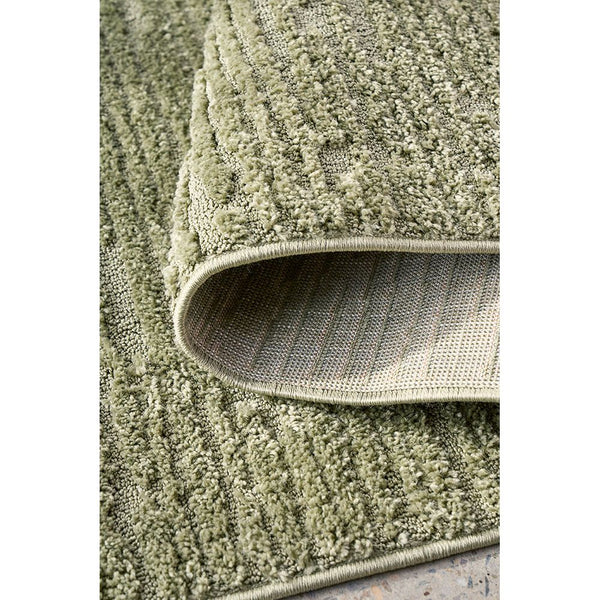 Green textured modern rug with raised pattern and soft polyester pile, folded edge detail.