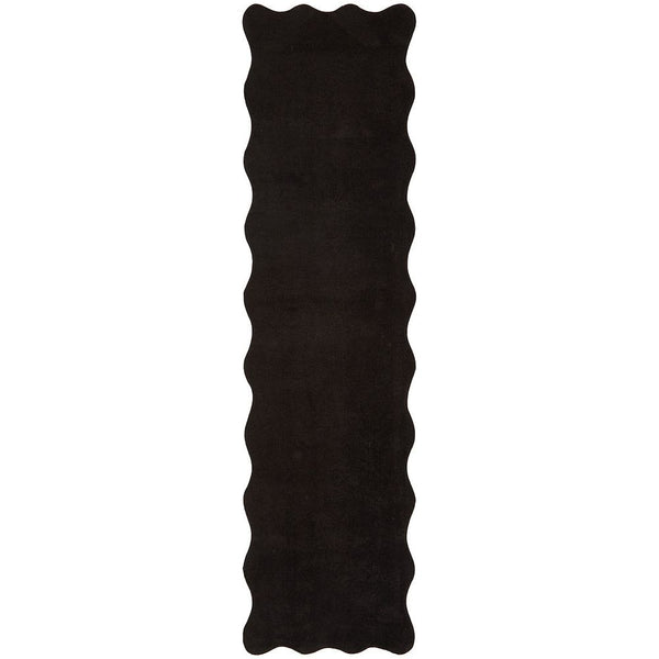 Long narrow black rug with scalloped edges and a smooth, velvety texture.