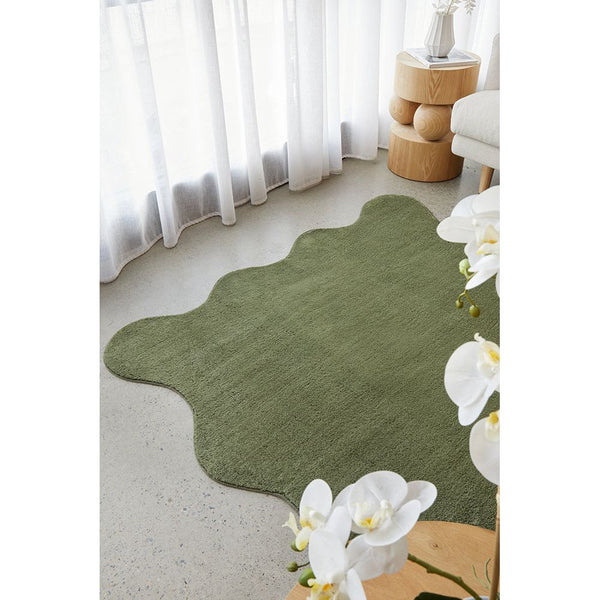 Modern green polyester rug with irregular wavy edges on polished floor.