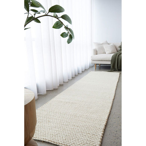Cream natural wool and jute runner rug with textured weave on light floor in bright room.