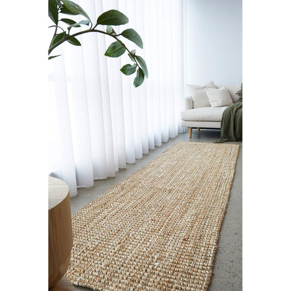 Natural jute runner rug with textured weave on light flooring in bright room.