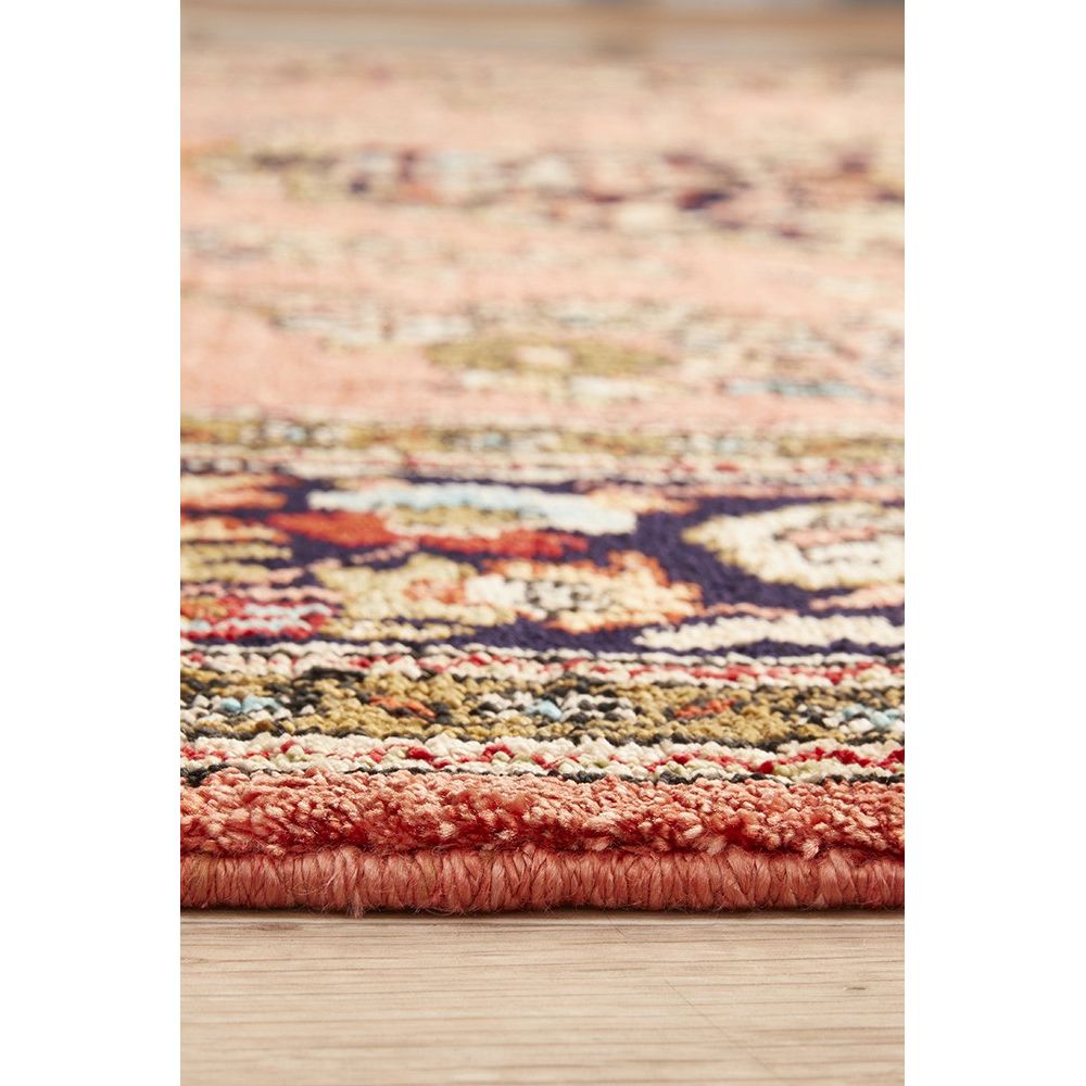 Close-up of a multicolored patterned hand knotted Persian silk rug on a wooden floor.