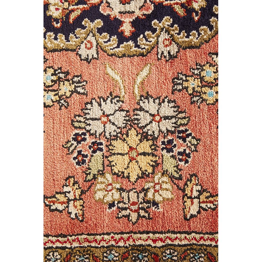 Close-up of a patterned hand knotted Persian silk rug with intricate designs.