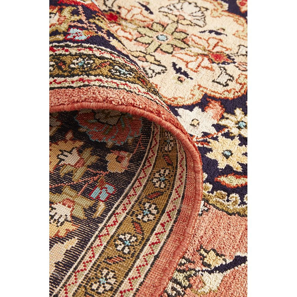 Close-up of a patterned hand knotted Persian silk rug with intricate motifs.