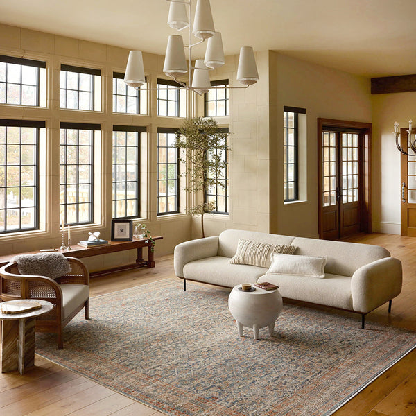 Large transitional rug with blue and earth tone textured patterns in a bright, modern living room.