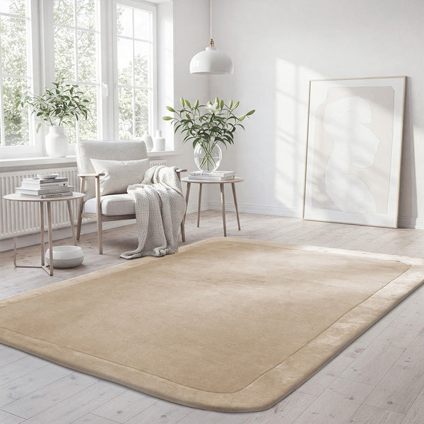 Beige wool viscose rug with curved border and soft texture in bright modern living room.
