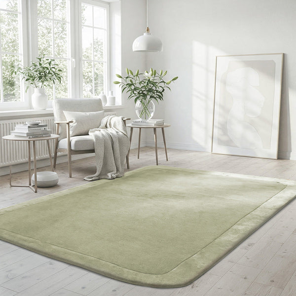 Soft green wool viscose rug with curved border in bright, minimalist living space.