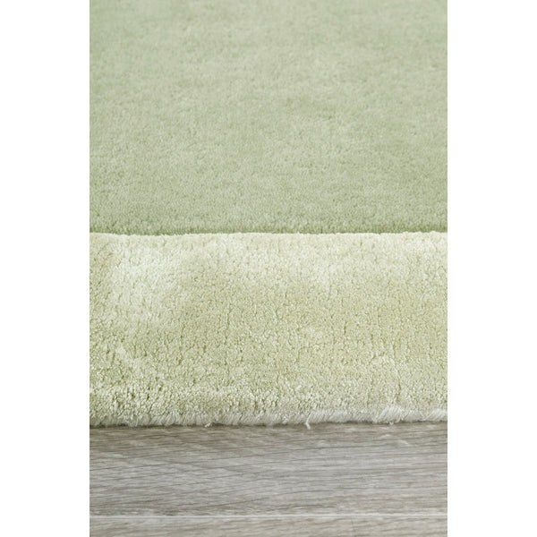 Soft green wool-viscose rug with plush hand-tufted texture and subtle curved border detail.