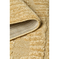 Close-up of a textured gold coloured rug with a focus on the edge.