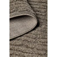 Close-up of a textured brown rug with a folded corner.